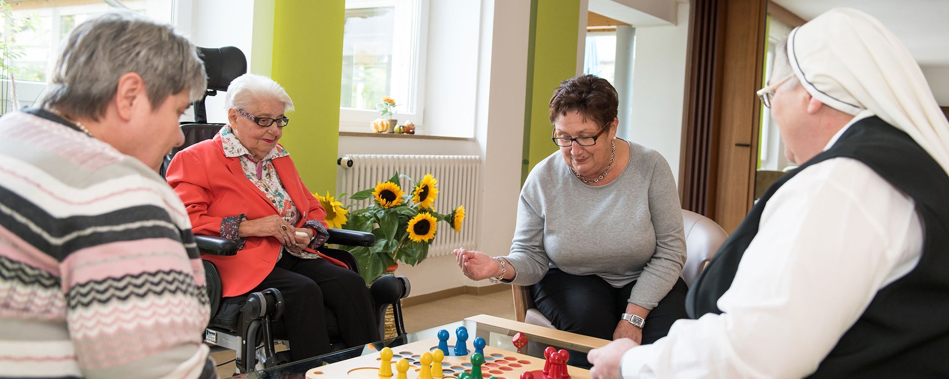 Drei Bewohnerinnen und eine Ordensschwester spielen "Mensch ärgere Dich nicht!"