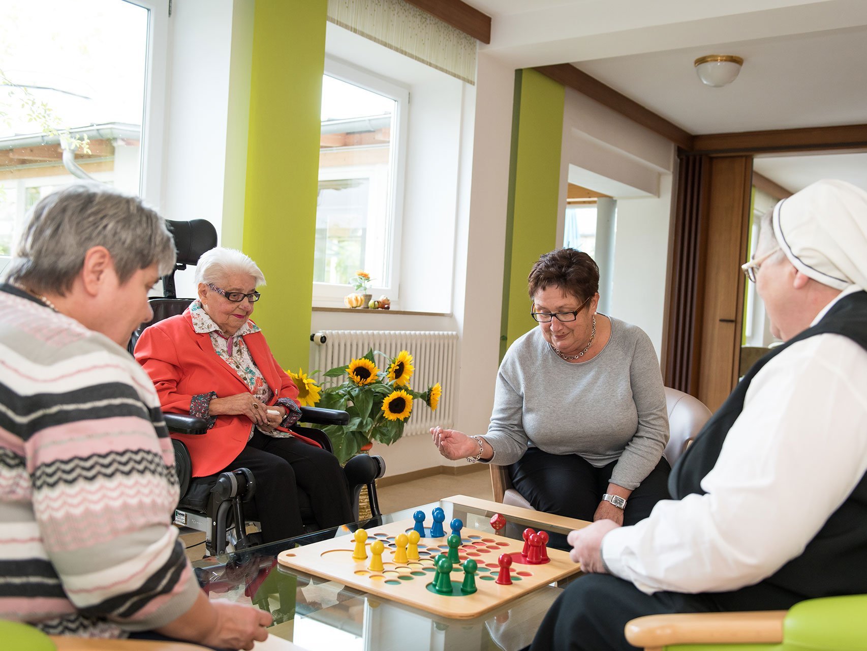 Drei Bewohnerinnen und eine Ordensschwester spielen "Mensch ärgere Dich nicht!"