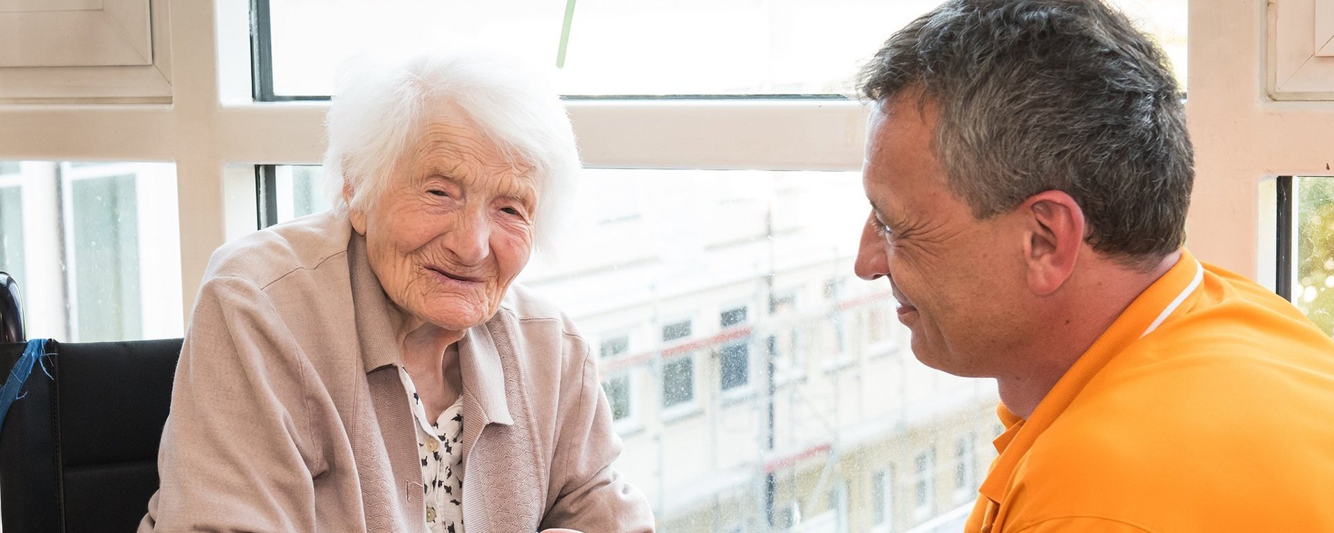 Ein Pfleger hält die Hände einer Bewohnerin - beide lächeln